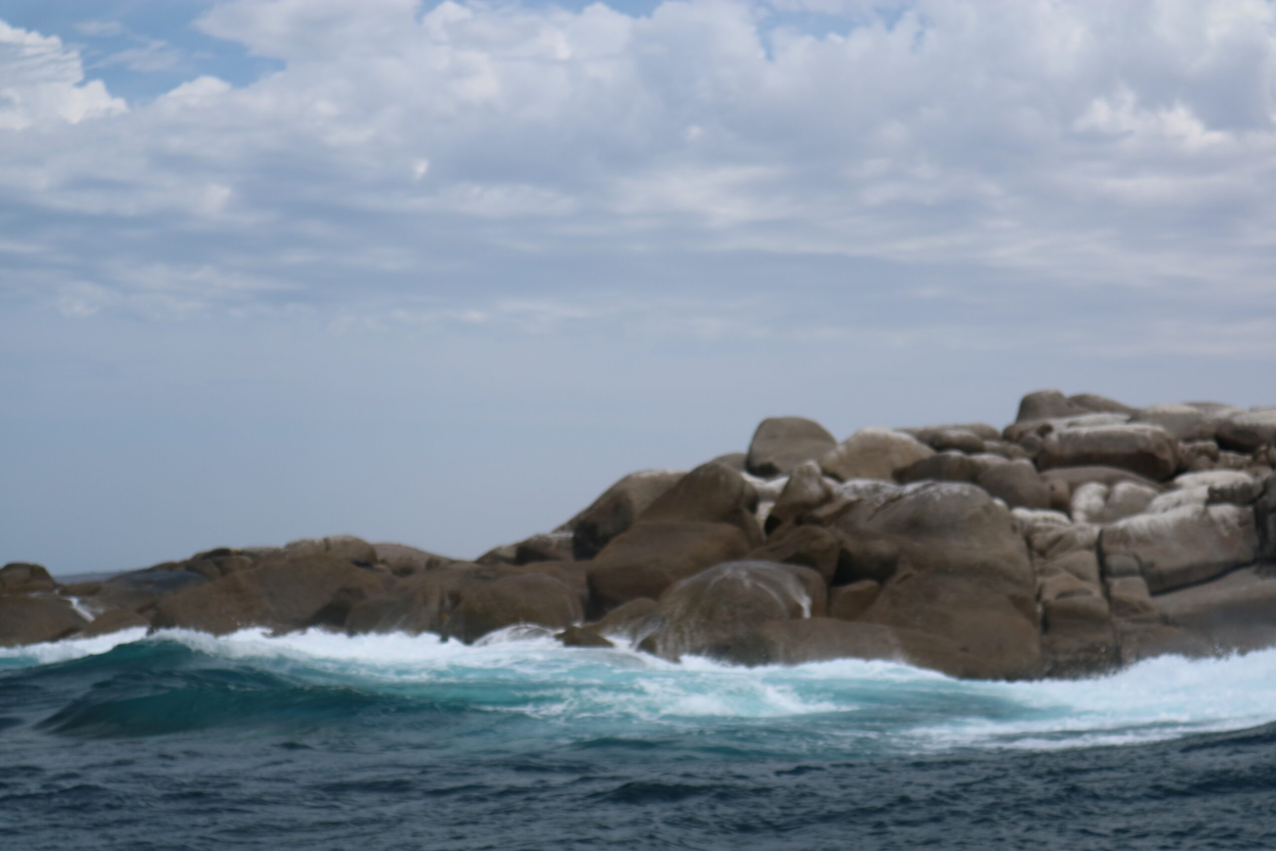 Waves slapping against grey rocks before a cloudy sky.